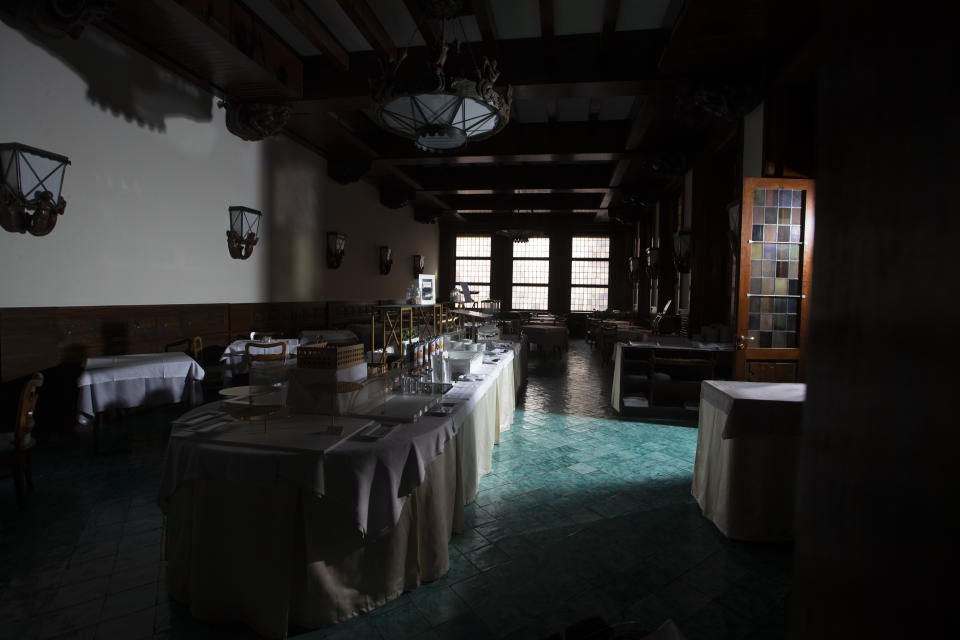 In this Tuesday, May 12, 2020 photo, the restaurant hall of the Hotel Meditarraneo Bettoja, is in the dark as the hotel is currently closed to the public after lockdown measures to prevent the spread of COVID-19 brought national and International leisure travel to a halt, in Rome. (AP Photo/Alessandra Tarantino)