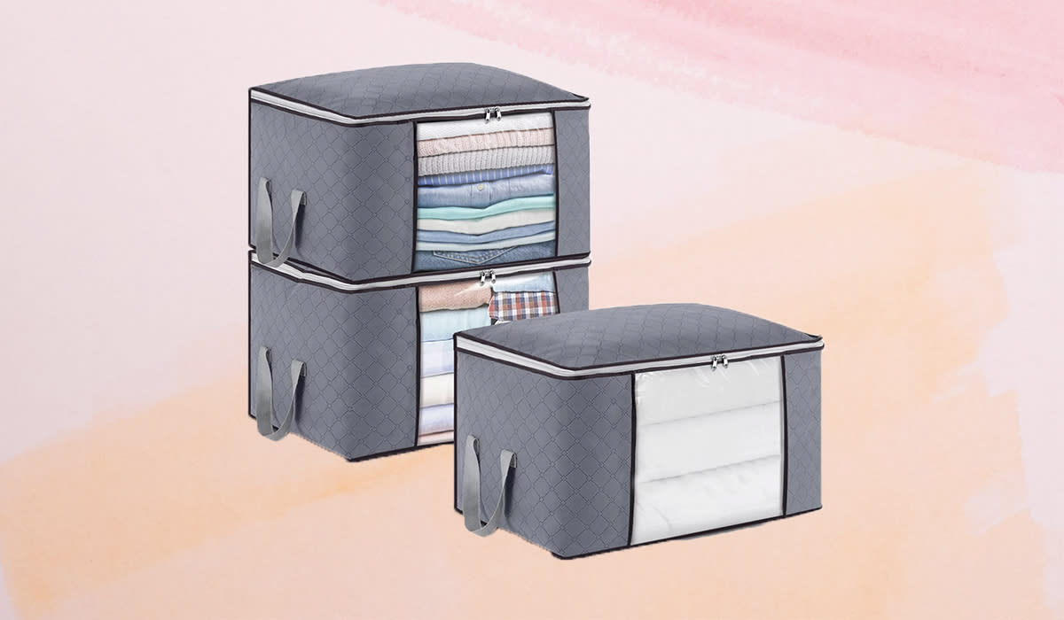 Two storage boxes with textile carrying handles, a tall one neatly packed with linens, and a small one packed with white towels.
