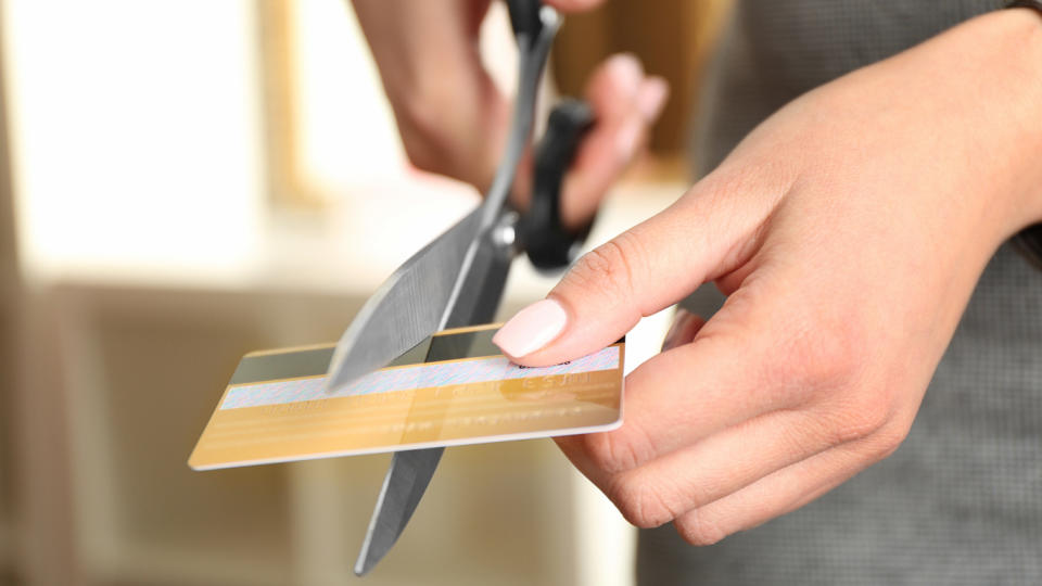 woman cutting credit card with scissors