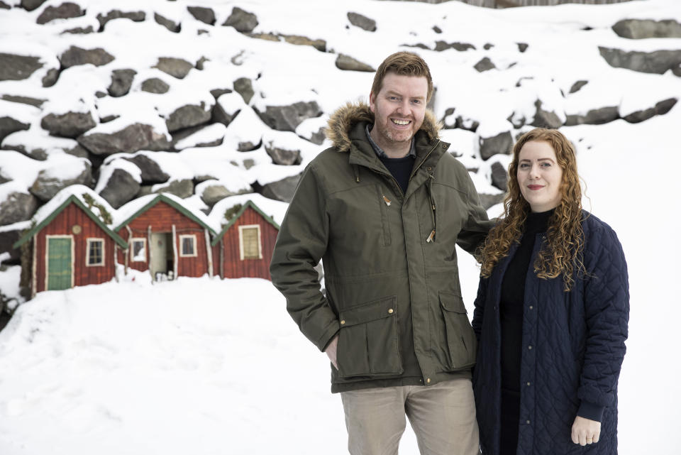 Orlygur Orlyson, left, and Johanna Baldursdottir pose for photographs in front of three elf homes, a location that appeared in the comedy "Eurovision Song Contest: The Story of Fire Saga," in Húsavík, Iceland, on Thursday, April 8, 2021. Húsavík (My Hometown)", a song from the film, is nominated for a best original song Oscar. The people of the small town of only 2,300 have staged a grassroots Oscar campaign on behalf of the song and adopted it as a de facto local anthem. Orlygur, or Orly as he is known, is the organizer of the Oscar campaign. (AP Photo/Brynjar Gunnarsson)