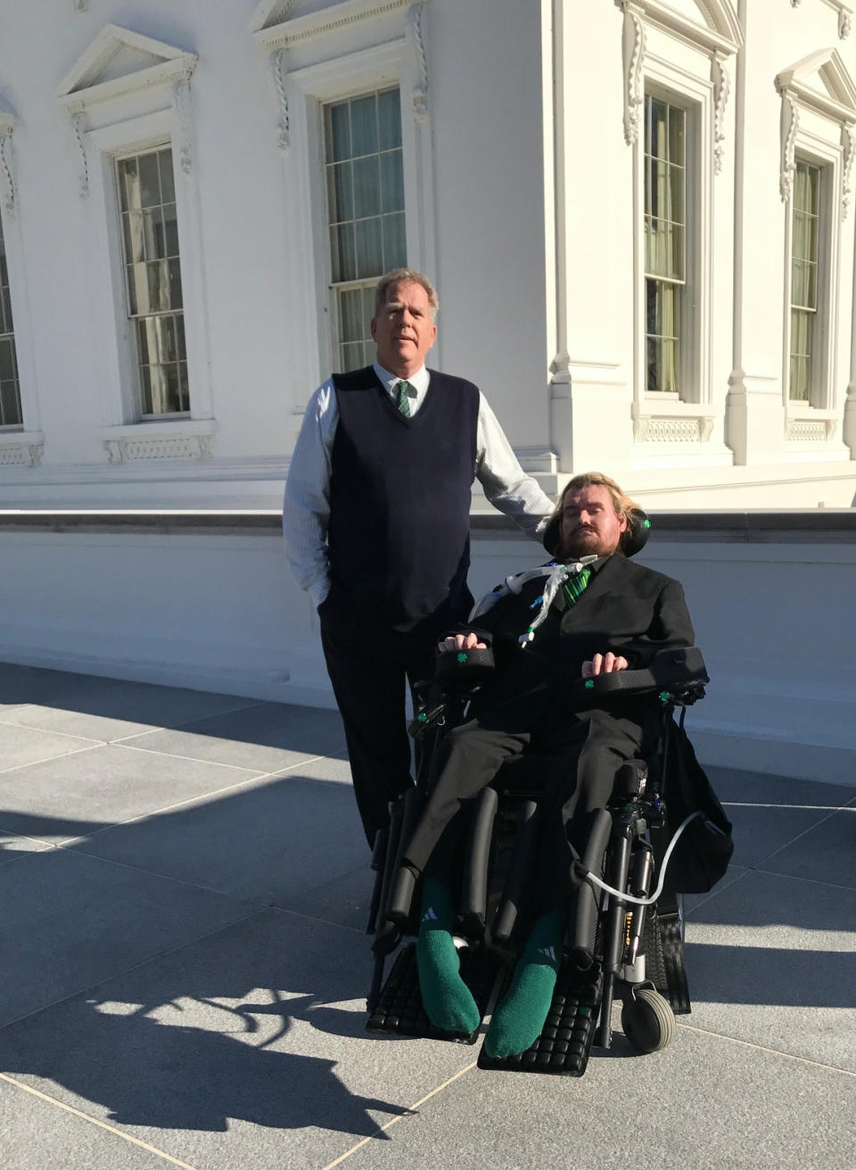 In this photo provided by Sayreville Mayor Kennedy O'Brien, Patrick Sean O'Brien, who suffers from amyotrophic laterals sclerosis, or ALS, poses for a photo with his father Kennedy O'Brien, left, outside the White House on Thursday, March 16, 2017, in Washington. Kennedy O'Brien says the White House "moved heaven and earth" to get his 42-year-old son to Thursday night's dinner with President Donald Trump and Irish Prime Minister Enda Kenny. (Kennedy O'Brien via AP)