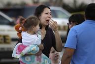 A woman holds her child after San Antonio police helped her and other shoppers exit the Rolling Oaks Mall, Sunday, Jan. 22, 2017, in San Antonio, after a deadly shooting. Authorities say several were injured after a robbery at the shopping mall. (AP Photo/Eric Gay)