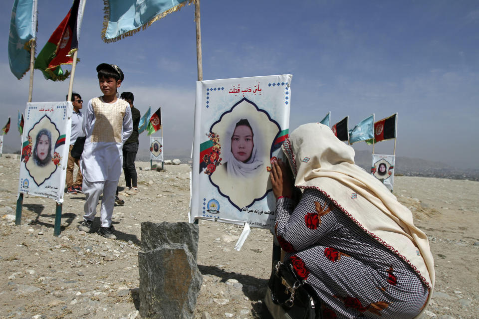 An Afghan woman cries next to the grave of her daughter, adorned with her picture, on the outskirts of Kabul, Afghanistan, Monday, Sept 14, 2020. Scores of friends and families of students who were killed in local conflicts are gathering in a cemetery to call for a permanent countrywide ceasefire from the parties to the intra-Afghan peace conference taking place in Doha, Qatar. (AP Photo/Rahmat Gul)