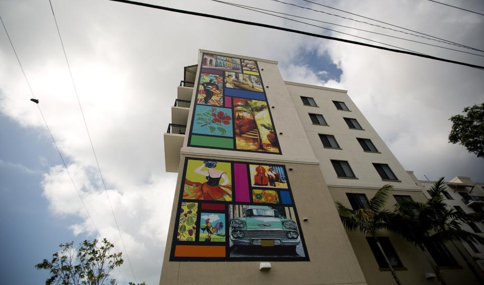 This May 1, 2014 photo shows a large mural on the side of an apartment building along Calle Ocho (Eighth Street) in Miami's Little Havana. Once a refuge for Cuban exiles rekindling the tastes and sounds a lost home, today Miami’s Little Havana is a mosaic of cultures and a popular tourist destination. (AP Photo/J Pat Carter)