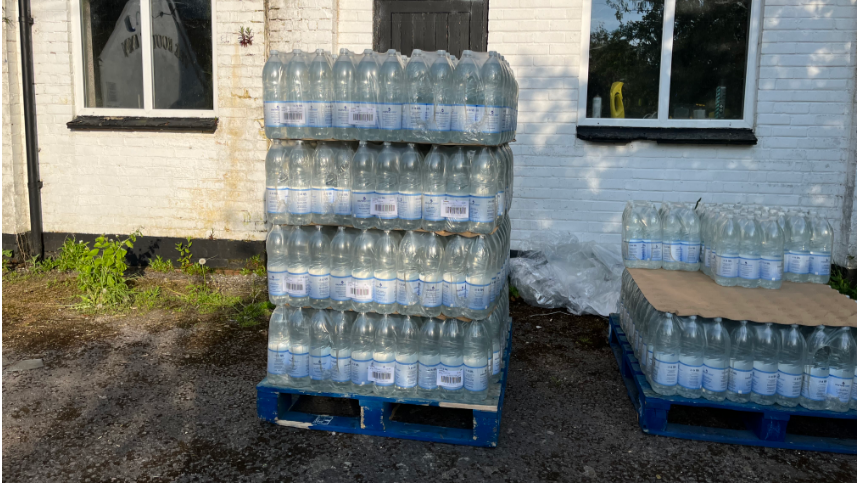 Hundreds of water bottles in a stack outside a property