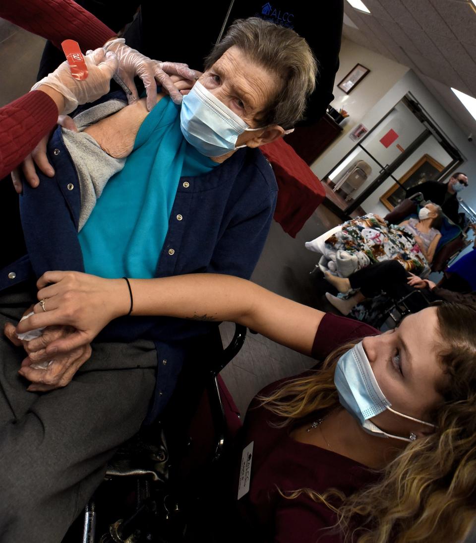 Alice Lorraine Center resident Donna Brett holds the hand of direct care worker Kayla Stanley as she receives her first dose of Moderna COVID-19 vaccine January 14, 2021 by a member of the Walgreens Immunizations Services.