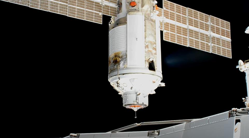 nauka module spaceship with solar array wings approaches international space station