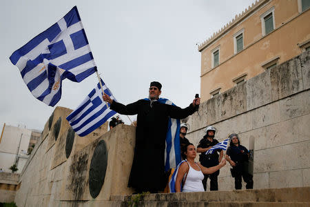 A Greek Orthodox monk waves a Greek flag during a demonstration against the agreement reached by Greece and Macedonia to resolve a dispute over the former Yugoslav republic's name, in Athens, Greece, June 16, 2018. REUTERS/Costas Baltas