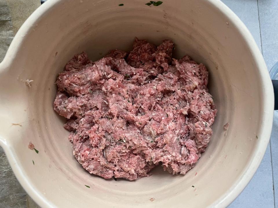 ground meat mixture for meatballs in a ceramic mixing bowl