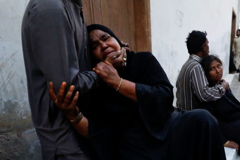 People mourn the death of a relative, who was killed with others in a stampede during handout distribution, in Karachi