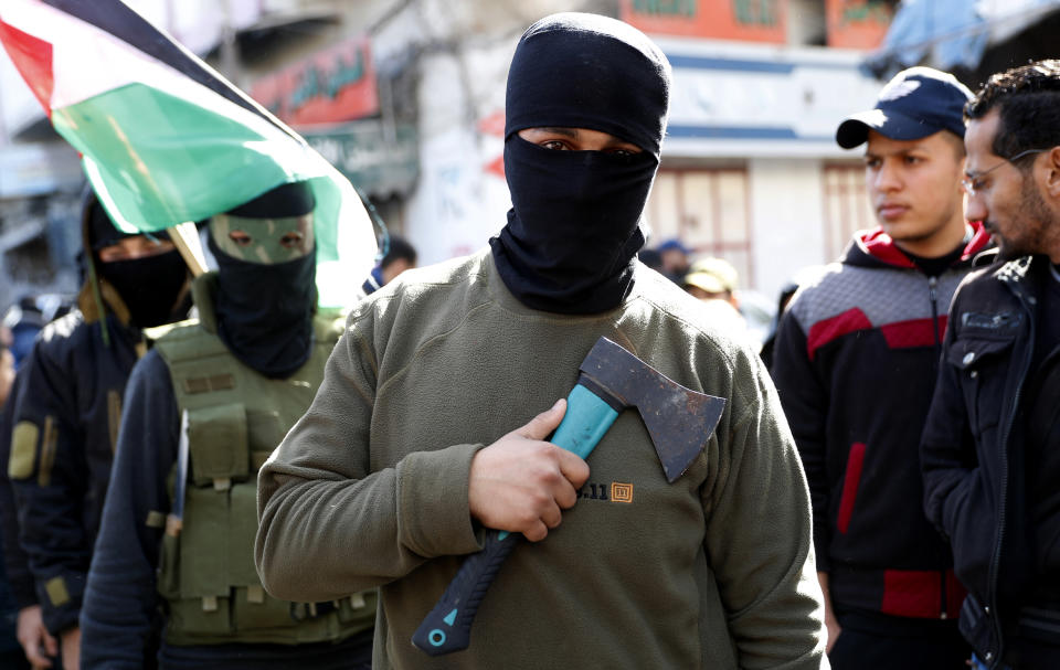 Masked member of Hamas holds an axe on his chest as others wave their national flags during a protest against the Mideast plan announced by U.S. President Donald Trump, after the Friday prayer at the main road in Gaza City, Friday, Jan. 31, 2020. (AP Photo/Adel Hana)