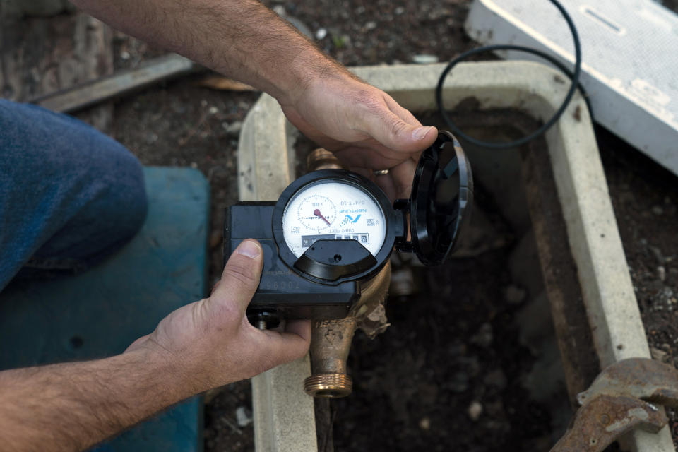 CORRECTS SPELLING TO AGOURA HILLS NOT AGORA HILLS Cason Gilmer, a senior field customer service representative from the Las Virgenes Municipal Water District, installs an advanced water metering system in Agoura Hills, Calif., Wednesday, Jan. 5, 2022. The wealthy enclave along the Santa Monica Mountains that is haven for celebrities has taken aggressive steps to try to limit water use during California's drought, including lowering the thresholds for fines for those who go over their "water budgets" and threatening to add restrictors to pipes that limit water flow to customers who repeatedly fail to conserve. (AP Photo/Jae C. Hong)