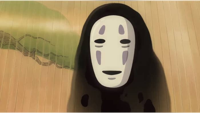 Animated character No-Face from the film 'Spirited Away' standing on a wooden floor