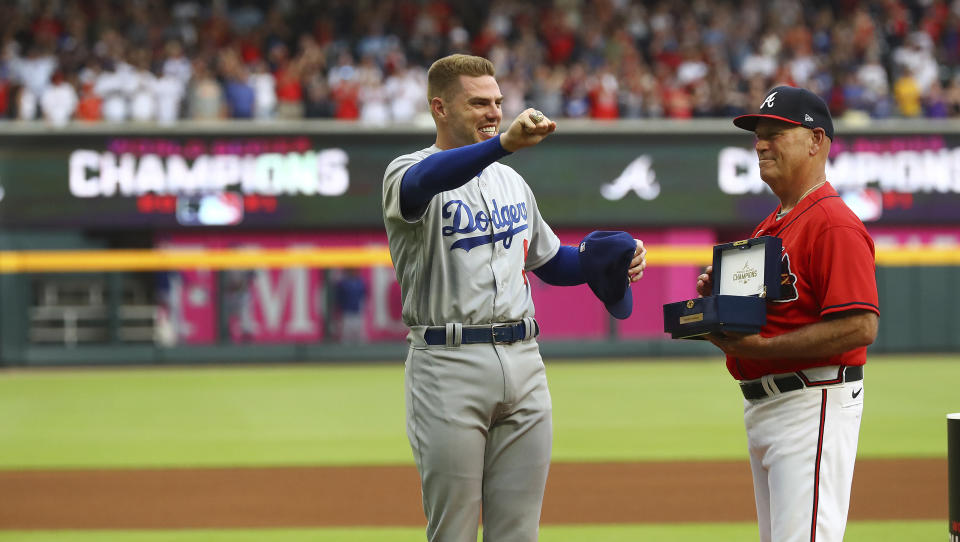 Atlanta Braves manager Brian Snitker, right, presents former Braves first baseman Freddie Freeman with his World Series Championship ring and Freeman displays it to fans during his return to Atlanta with the Los Angles Dodgers for a baseball game Friday, June 24, 2022, in Atlanta. (Curtis Compton/Atlanta Journal-Constitution via AP)