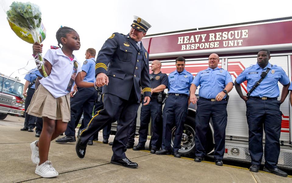 Dynasti Hartman walks hand-in-hand with Assistant Fire Chief Sam Castanza as members of Montgomery Fire and Rescue honor Hartman, a Forest Avenue Academic Magnet School student and daughter of injured firefighter Deandre Hartman, in Montgomery, Alabama, on Monday, May 22, 2023. Deandre Hartman was injured in a fire on May 14th and is being treated in the UAB Hospital Burn abd Trauma ICU.