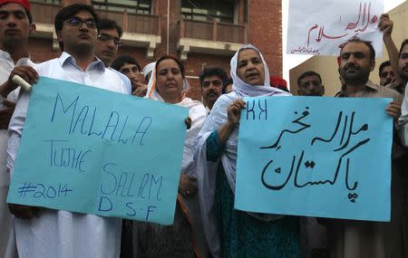 Members of the civil society hold placards to praise Malala Yousafzai, while celebrating her winning the Nobel Peace Prize, in Peshawar October 10, 2014. REUTERS/Fayaz Aziz