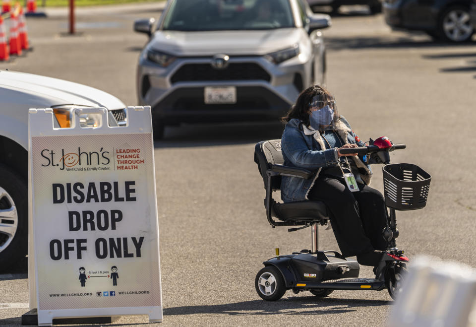 Veronica Lopez, who has Spina bifida, arrives for her vaccine appointment at the St. John's Well Child and Family Center's COVID-19 vaccination site at the East Los Angeles Civic Center in Los Angeles, Thursday, March 4, 2021. California will begin setting aside 40% of all vaccine doses for the state's most vulnerable neighborhoods in an effort to inoculate people most at risk from the coronavirus more quickly. (AP Photo/Damian Dovarganes)