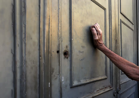 FILE PHOTO: A pensioner leans against the main door of a branch of the National Bank as he waits to receive part of his pension in Athens, Greece, July 7, 2015. REUTERS/Yannis Behrakis/File photo