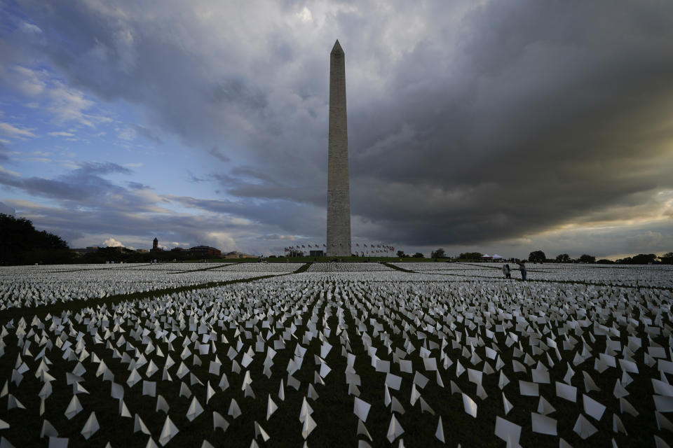 With the Washington Monument in the background, people look at white flags that are part of artist Suzanne Brennan Firstenberg's temporary art installation, "In America: Remember," in remembrance of Americans who have died of COVID-19, on the National Mall in Washington, Friday, Sept. 17, 2021. The installation consists of more than 630,000 flags. (AP Photo/Brynn Anderson)