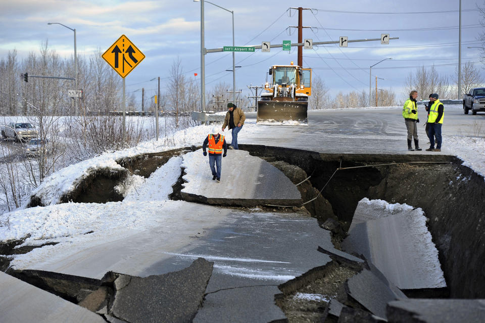 FILE - In this Friday, Nov. 30, 2018 file photo, workers inspect a road that collapsed during an earthquake in Anchorage, Alaska. The collapsed roadway that became an iconic image of the destructive force of a magnitude 7.0 earthquake and its aftershocks was repaired just days after the quake. The off-ramp connecting Minnesota Drive and Ted Stevens Anchorage International Airport reopened Tuesday, Dec. 4, 2018, with shoulder work completed Wednesday. (AP Photo/Mike Dinneen, File)