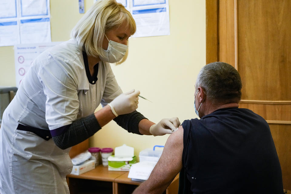 A resident takes an anti-coronavirus vaccine in Morshyn, Ukraine, Tuesday, Nov. 16, 2021. In Morshyn, a scenic town nestled at the Carparthian foothills in the Lviv region, 74% of 3,439 residents have been fully vaccinated. A small spa town in western Ukraine stands out in a country where just under a quarter of the population has received coronavirus vaccines. (AP Photo/Efrem Lukatsky)