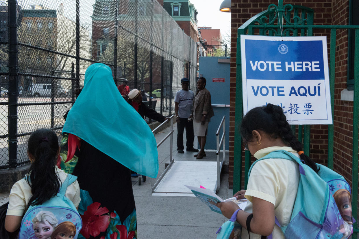 A woman with a Muslim headscarf walks past a voting sign at PS 3 on April 19, 2016 in the Brooklyn borough of New York City. (Stephanie Keith/Getty Images)