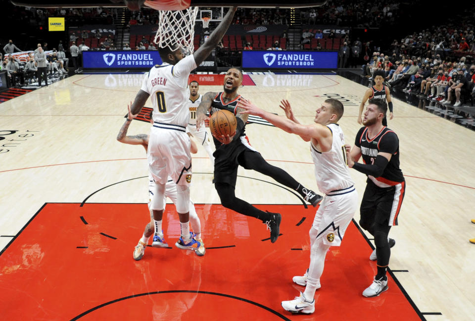 Portland Trail Blazers guard Damian Lillard, center, drives to the basket on Denver Nuggets forward JaMychal Green, left, and center Nikola Jokic, right, during the first half of Game 4 of an NBA basketball first-round playoff series in Portland, Ore., Saturday, May 29, 2021. The Blazers won 1115-95. (AP Photo/Steve Dykes)