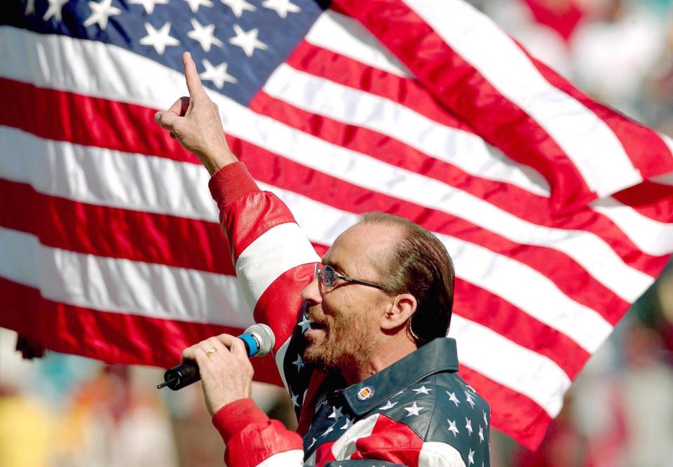 Rick Wilson/staff--1/1/01--An American Flag flaps in the breeze in the background as Lee Greenwood sings "Proud to be an American" during a Celebration of Freedom prior to the start of the Gator Bowl Tuesday afternoon at Alltel Stadium.