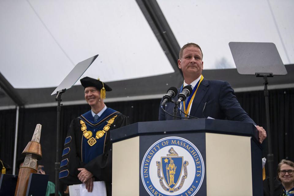In this photo provided by University of Massachusetts Dartmouth, is billionaire Robert Hale, right, onstage with UMass Dartmouth Chancellor Mark Fuller, left, at the graduation ceremony Thursday, May 16, 2024, in Dartmouth, Mass. Hale gifted graduates at the University of Massachusetts Dartmouth each with $1,000., with the condition that they give $500 away. Hale revealed the gift to more than 1,100 graduates. (Karl Christoff Dominey/University of Massachusetts Dartmouth via AP)