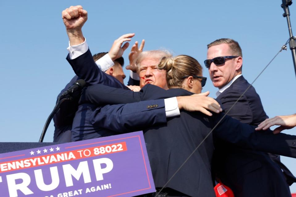 Anna Moneymaker of Getty Images took this photo of Trump gesturing toward the crowd of supporters as he was being hauled away by Secret Service agents on Saturday. Getty Images