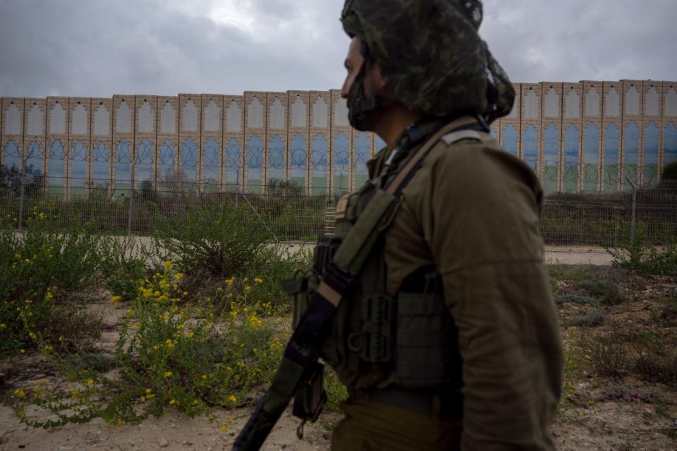 An IDF officer walks past the protective barriers near the border fence with the Gaza Strip on November 19, 2023 in Netiv HaAsara, Israel (Getty Images)