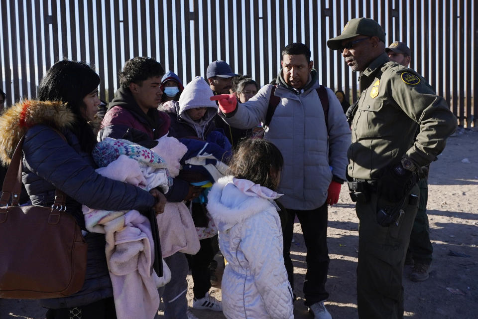 Luiz Velazquez, second from right, from Zacatecas, Mexico points to his family as he talks with a member of the U.S. Border Patrol as they join hundreds of migrants gathering along the border Tuesday, Dec. 5, 2023, in Lukeville, Ariz. (AP Photo/Ross D. Franklin)