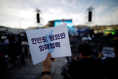 A man holds a placard that reads "Peace, reconciliation and cooperation on the Korean peninsula" during a rally to wish for a successful inter-Korean summit, in central Seoul, South Korea, April 21, 2018. REUTERS/Kim Hong-Ji