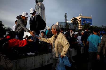 A volunteer gives water before departing with a caravan of migrants from El Salvador en route to the United States, in San Salvador, El Salvador, October 28, 2018. REUTERS/Jose Cabezas