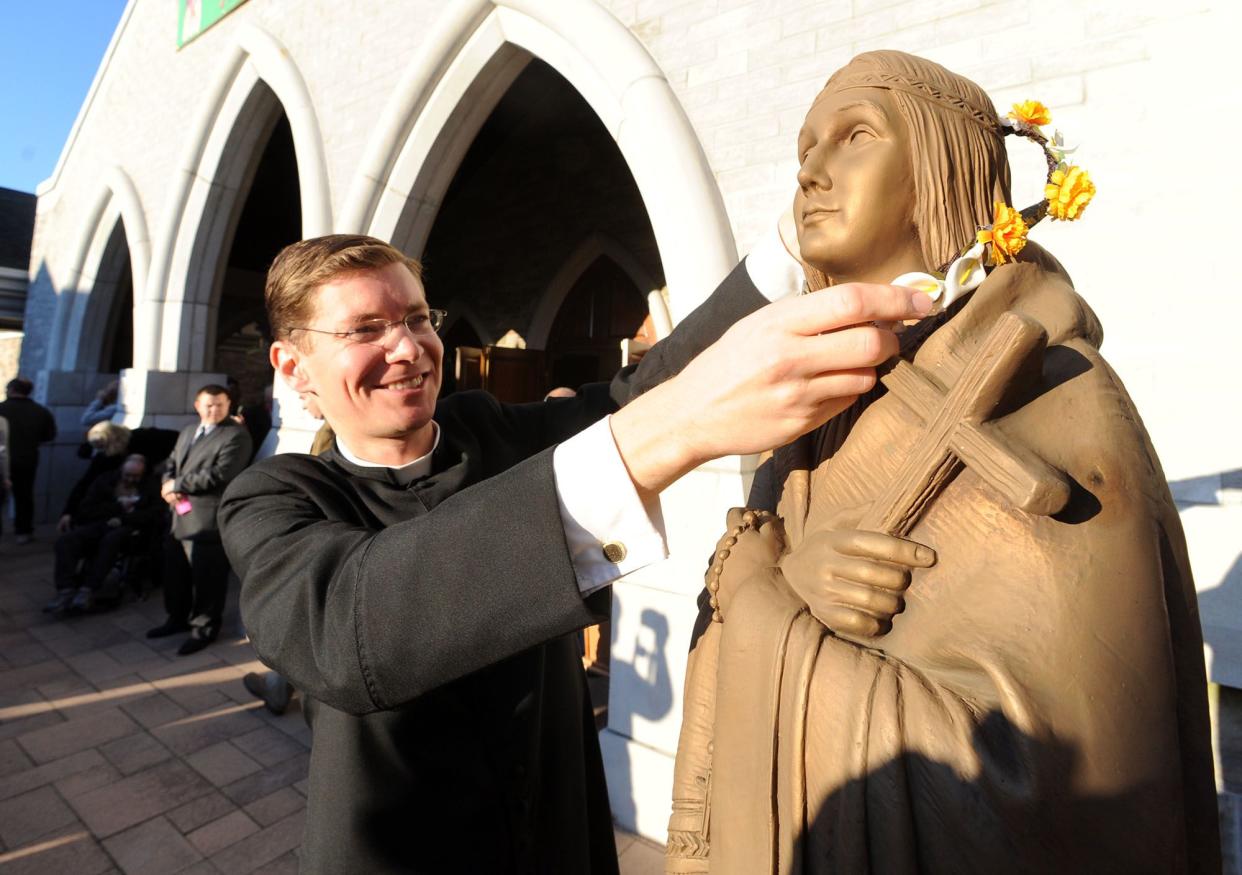 The Rev. Brian Graebe places flowers on a statue of Saint Kateri Tekakwitha Sunday, Oct. 21, 2012, at Saint Kateri Tekakwitha Roman Catholic Church in Lagrangeville, N.Y. 