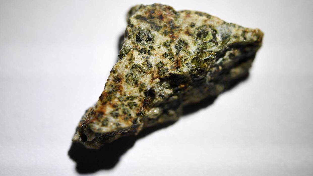  a light brown rock dotted with light green crystals 