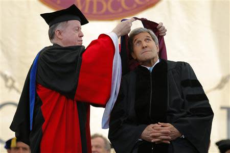 U.S. Secretary of State John Kerry ducks as he receives an honorary Doctor of Laws degree from college president William Leahy (L) during Commencement Exercises at Boston College in Boston, Massachusetts May 19, 2014. REUTERS/Brian Snyder