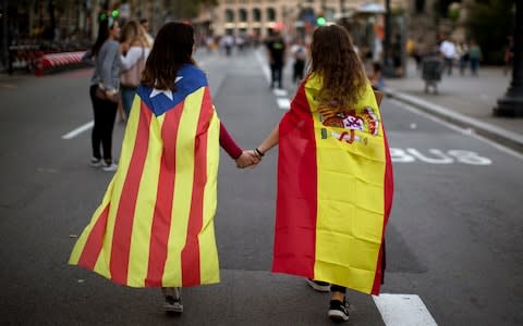 Irene Guszman, 15, wearing a Spanish flag and Mariona Esteve, 14, wearing an estelada or independence flag, take part at a demonstration in Barcelona last year - Credit: AP