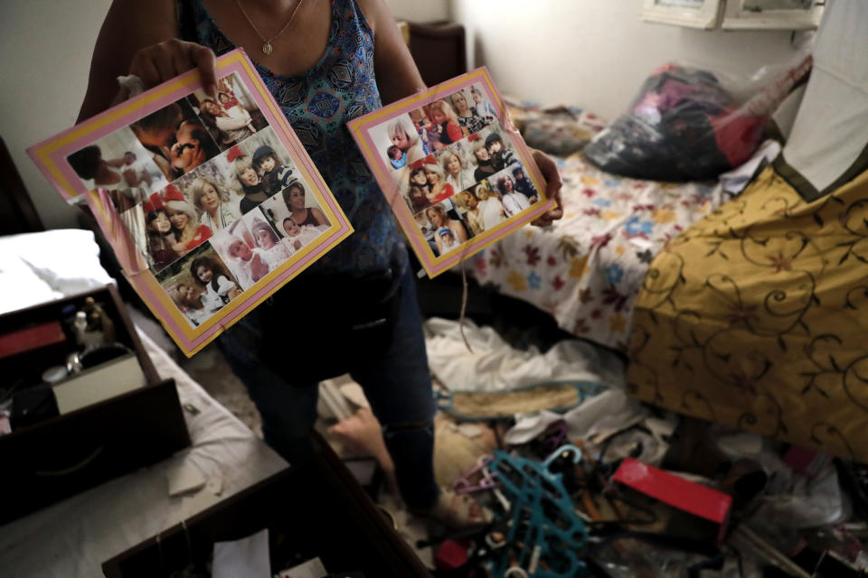 Image: A woman shows pictures of her family in her damaged home (Hussein Malla / AP)