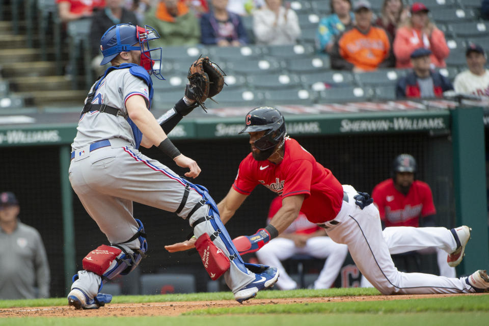 Cleveland Guardians' Amed Rosario scores on a two-run single by Owen Miller as Texas Rangers' Sam Huff waits for the throw during the third inning of the first game of a baseball doubleheader in Cleveland, Tuesday, June 7, 2022. (AP Photo/Phil Long)