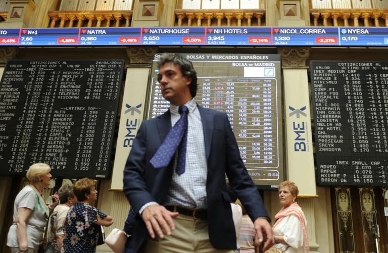 People stand Madrid stock exchange boards in Madrid on June 24, 2016