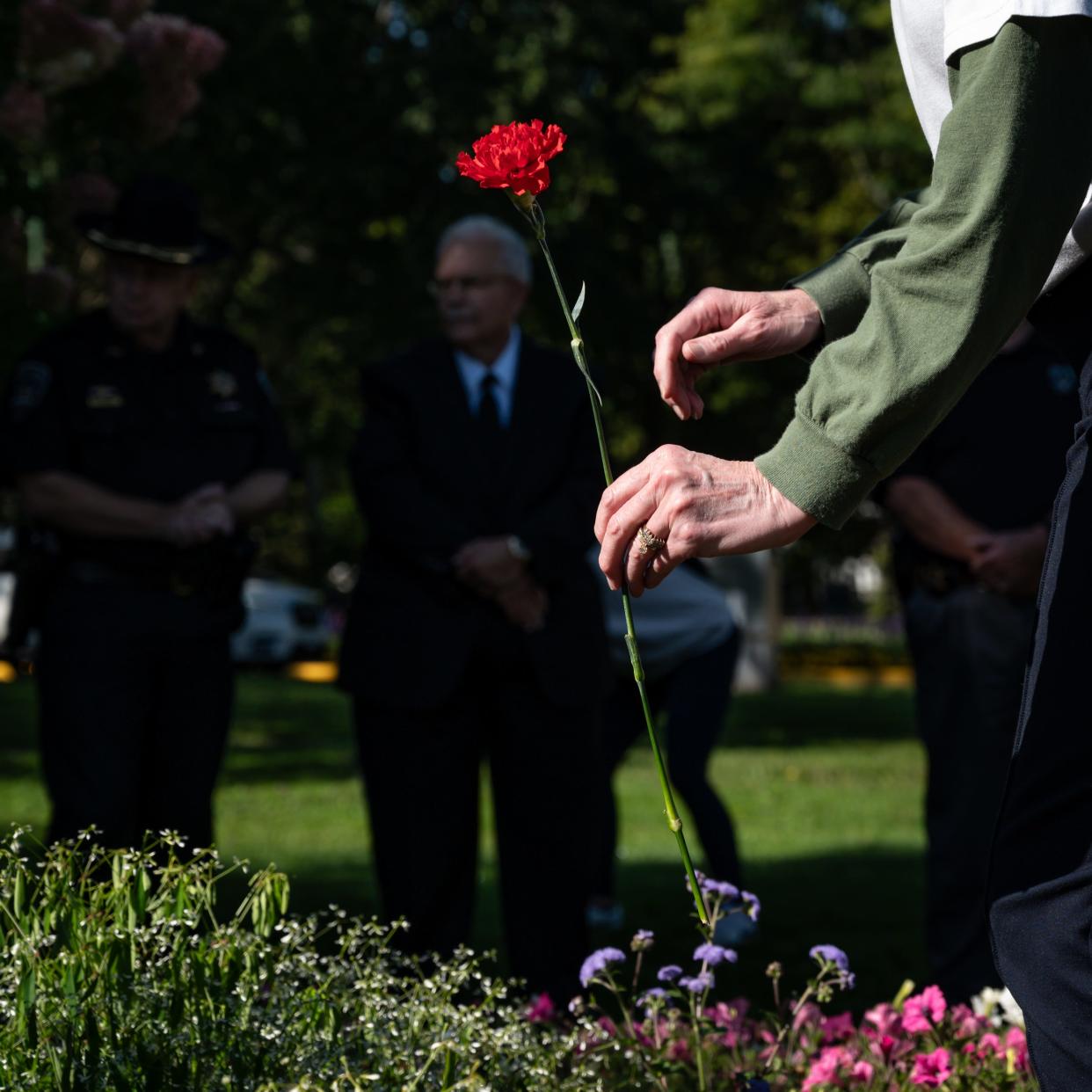 Vanessa Graham, of Ilion, places a carnation by Utica's 9/11 memorial in memory of her brother Don Kauth, a Utica native who died in the World Trade Center on Sept. 11, 2001. Graham took part in a ceremony at the memorial on the Memorial Parkway at Sherman Drive in Utica on Sept. 11, 2024.