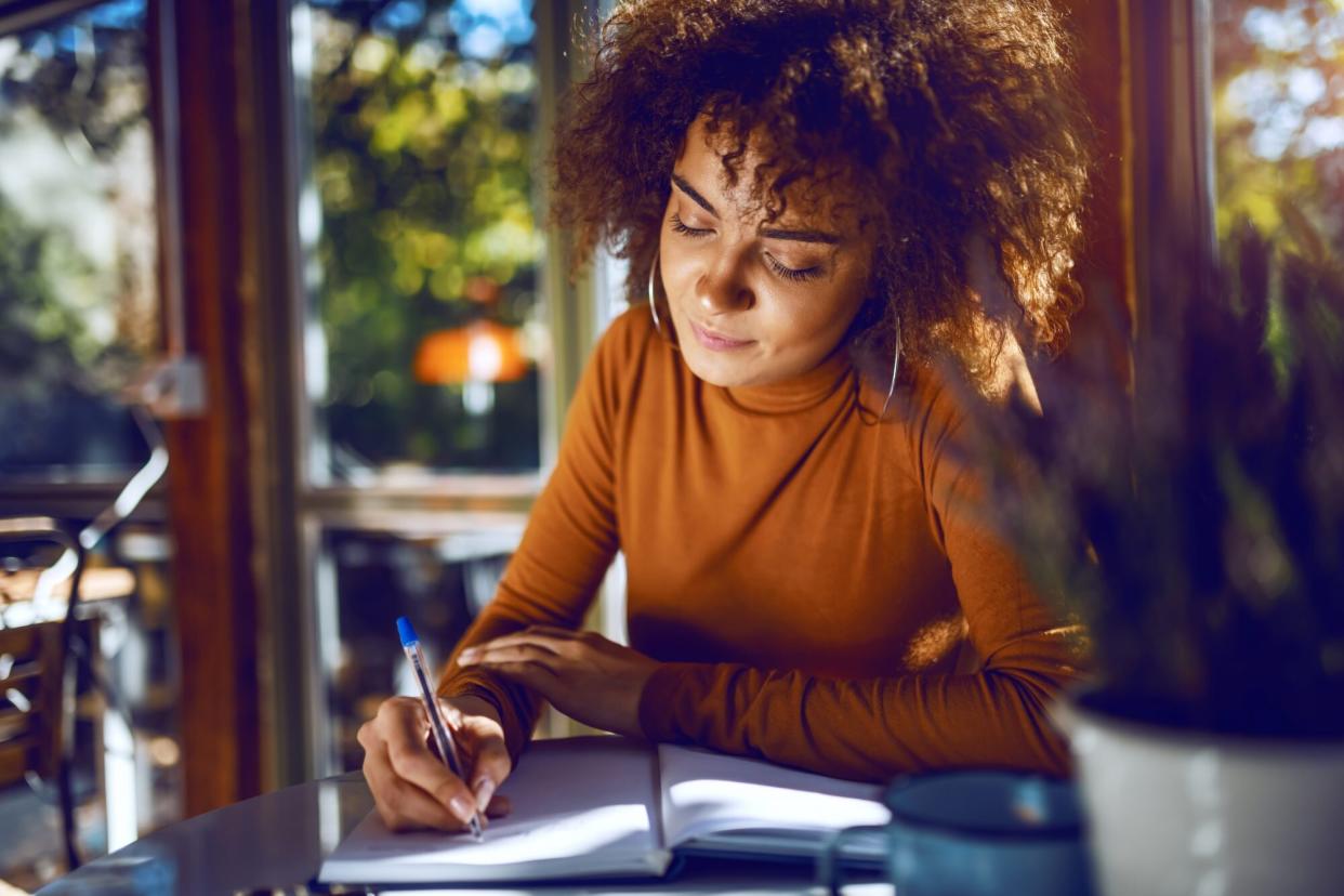 woman writing in notebook at cafe