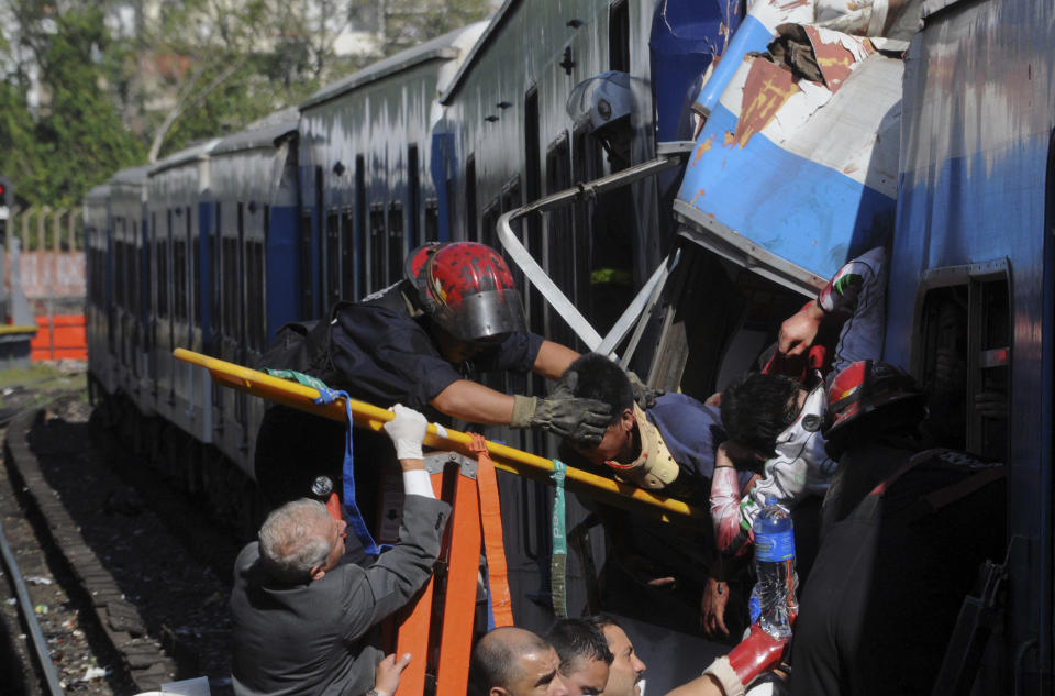 FILE - In this Feb. 22, 2012 file photo, firemen rescue wounded passengers from a commuter train after a collision in Buenos Aires, Argentina. A court in Argentina has sentenced on Wednesday, Oct. 10, 2018, the former planning minister Julio De Vido for his role in the 2012 train accident that left more than 50 people dead and hundreds injured. (AP Photo/Leonardo Zavattaro,Telam, File)