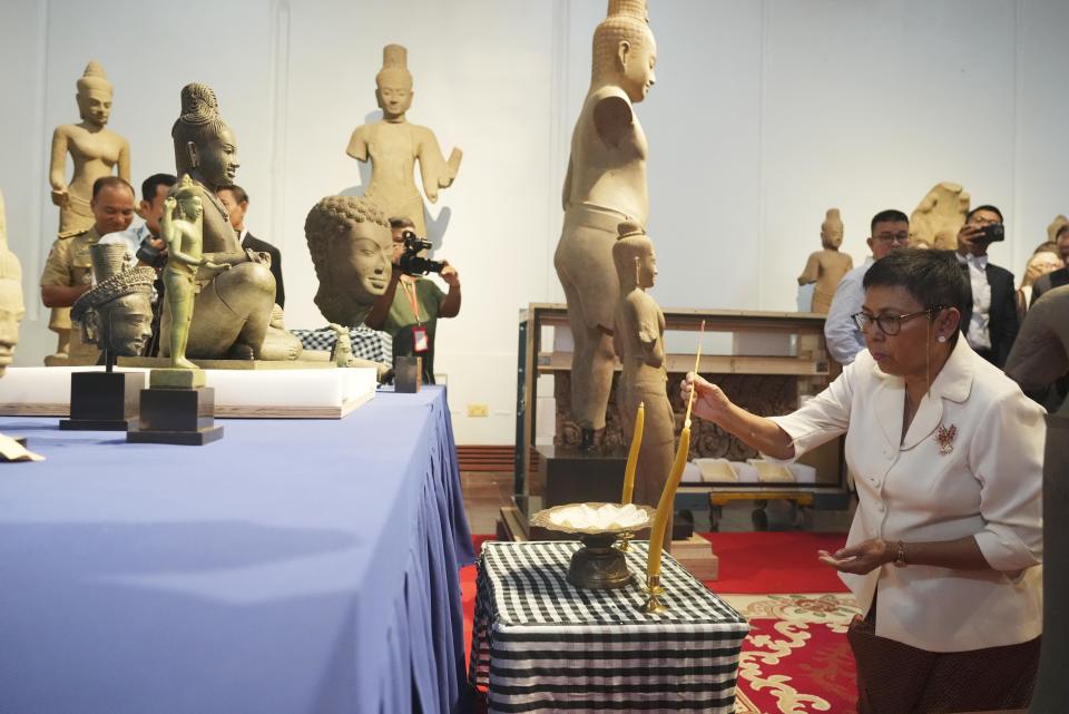 La ministra de Cultura y Bellas Artes de Camboya, Phoeurng Sackona, quema varitas de incienso frente a estatuas y artefactos durante una ceremonia oficial en el Museo Nacional de Camboya en Phnom Penh, Camboya, el jueves 4 de julio de 2024. (AP Photo/Heng Sinith)