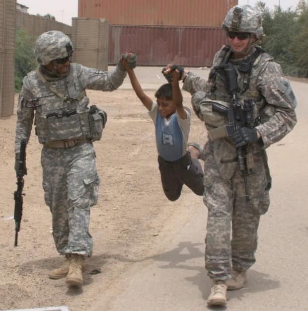 All three of the plaintiffs are U.S. military veterans. Here, Johnny Grays, left, is shown during an army deployment to Iraq in 2009 with a colleague and child.  