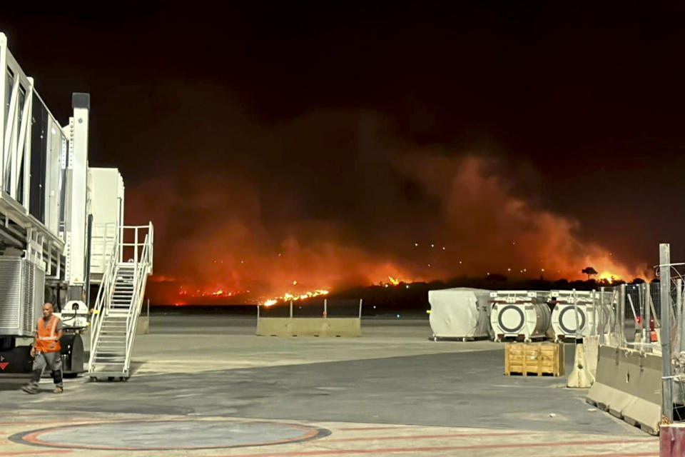 This photo provided by Palermo Airport Press Office shows plumes of fire and smoke covering the hills surrounding Palermo's airport, Sicily, Italy, late Monday night, July 24, 2023, causing its shutdown and leaving planes trapped on the tarmac. The airport reopened at 11am (9gmt) Tuesday 25 only for departing planes, after twentyfour flights were cancelled overnight and four were sent to the nearby airport in Trapani. (Palermo Airport Press Office via AP)