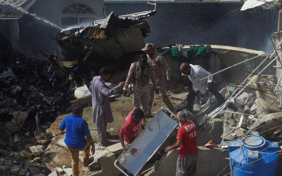 Rescue workers gather at the site after a Pakistan International Airlines flight crashed in a residential neighbourhood in Karachi on May 22, 2020.