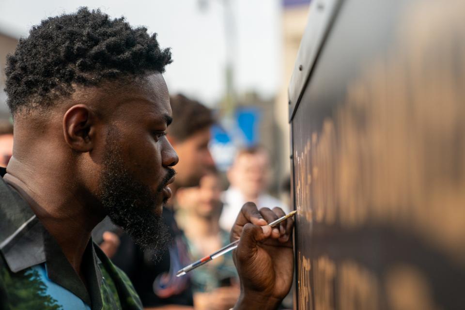 A person paints in the final letters of George Floyd's name at a statue unveiling in his honor at Flatbush Junction on June 19, 2021, in the Brooklyn borough of New York City.