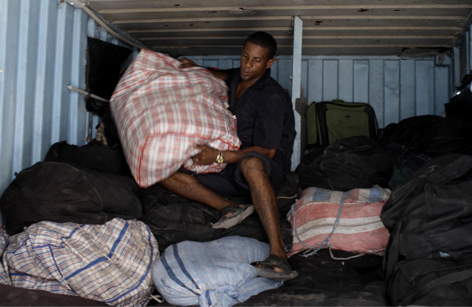 In this Aug 29, 2012 photo, Luis Manuel Dlas works to unload bags of imported clothing and accessories from a storage container, where self-employed vendors store their merchandise within an open market where the government allows licensed vendors to sell their goods in downtown Havana, Cuba. A jump in import taxes on Monday, Sept. 3 threatens to make life tougher for some of Cuba's new entrepreneurs who the government has been trying to encourage as it cuts a bloated workforce in the socialist economy. In Cuba, the average monthly wage is about $20. (AP Photo/Franklin Reyes)